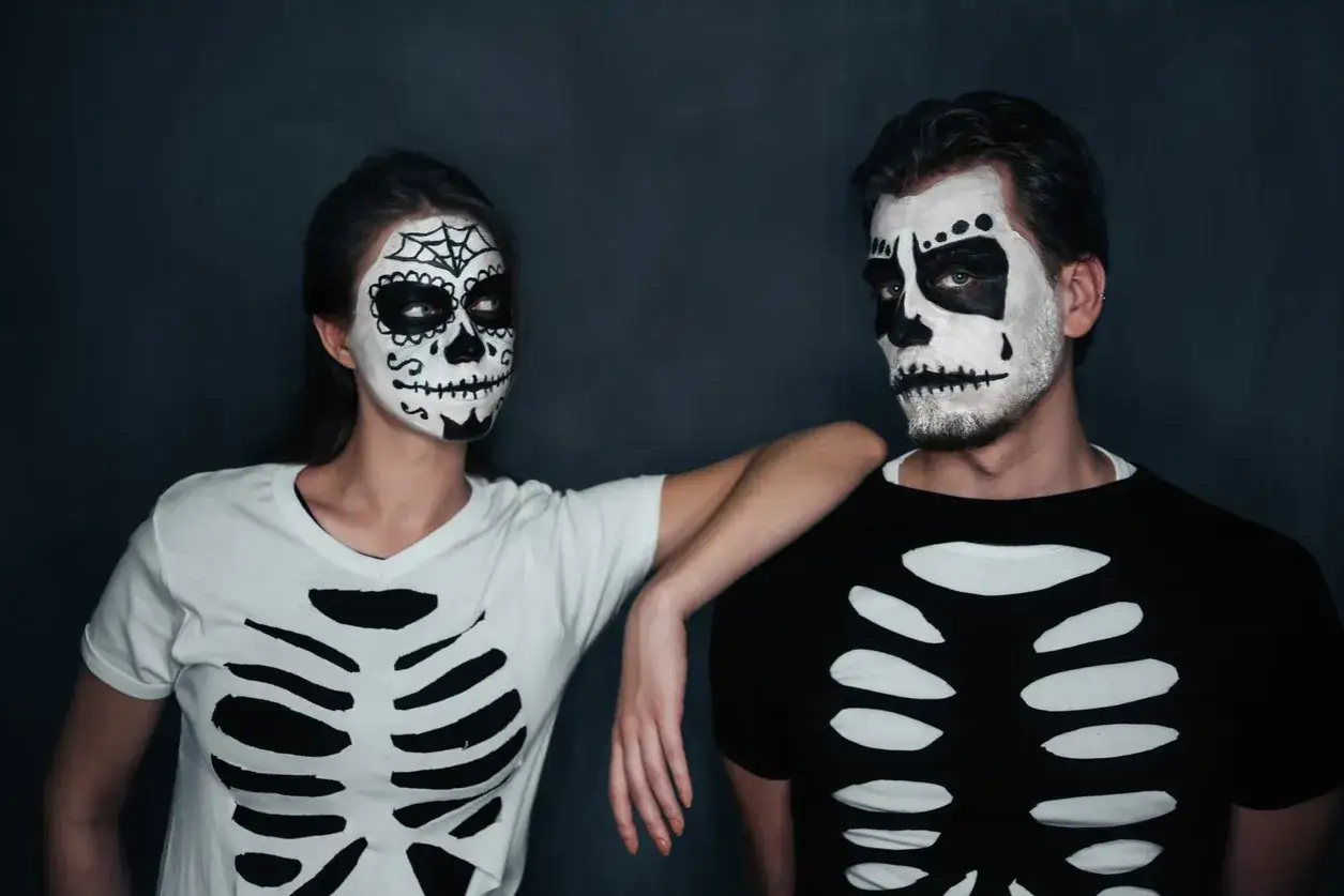 Coppia con trucco da teschio e magliette con scheletro, perfetti costumi horror fai da te per Halloween.