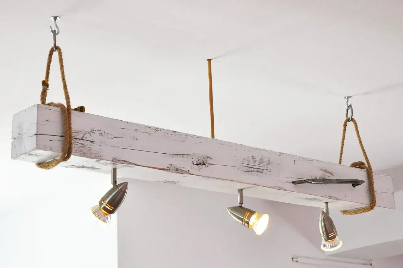 Lampadari in legno fai da te con faretti metallici, sospesi con corde rustiche a una trave sbiancata.
