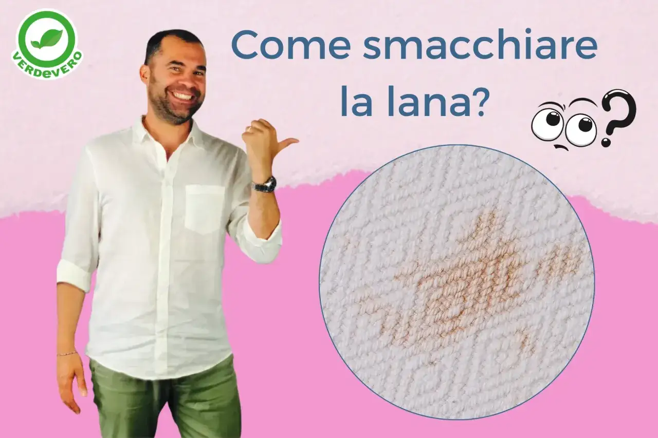 Uomo sorridente indica come sbiancare lana con bicarbonato, mostrando una macchia su tessuto bianco.