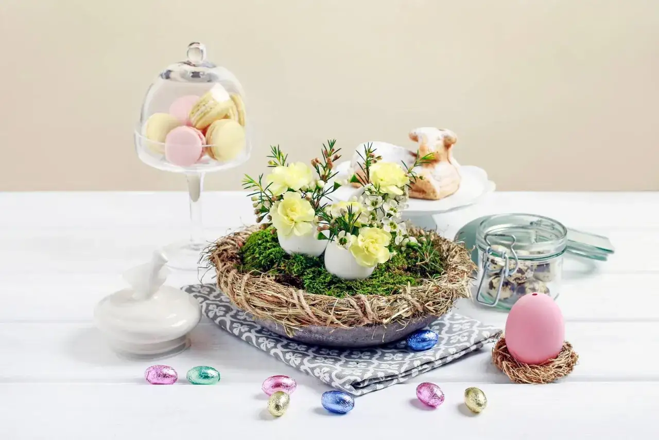 Deliziosi lavoretti per Pasqua: un nido con uova decorate e fiori, macarons, un agnello di zucchero e uova di cioccolato.