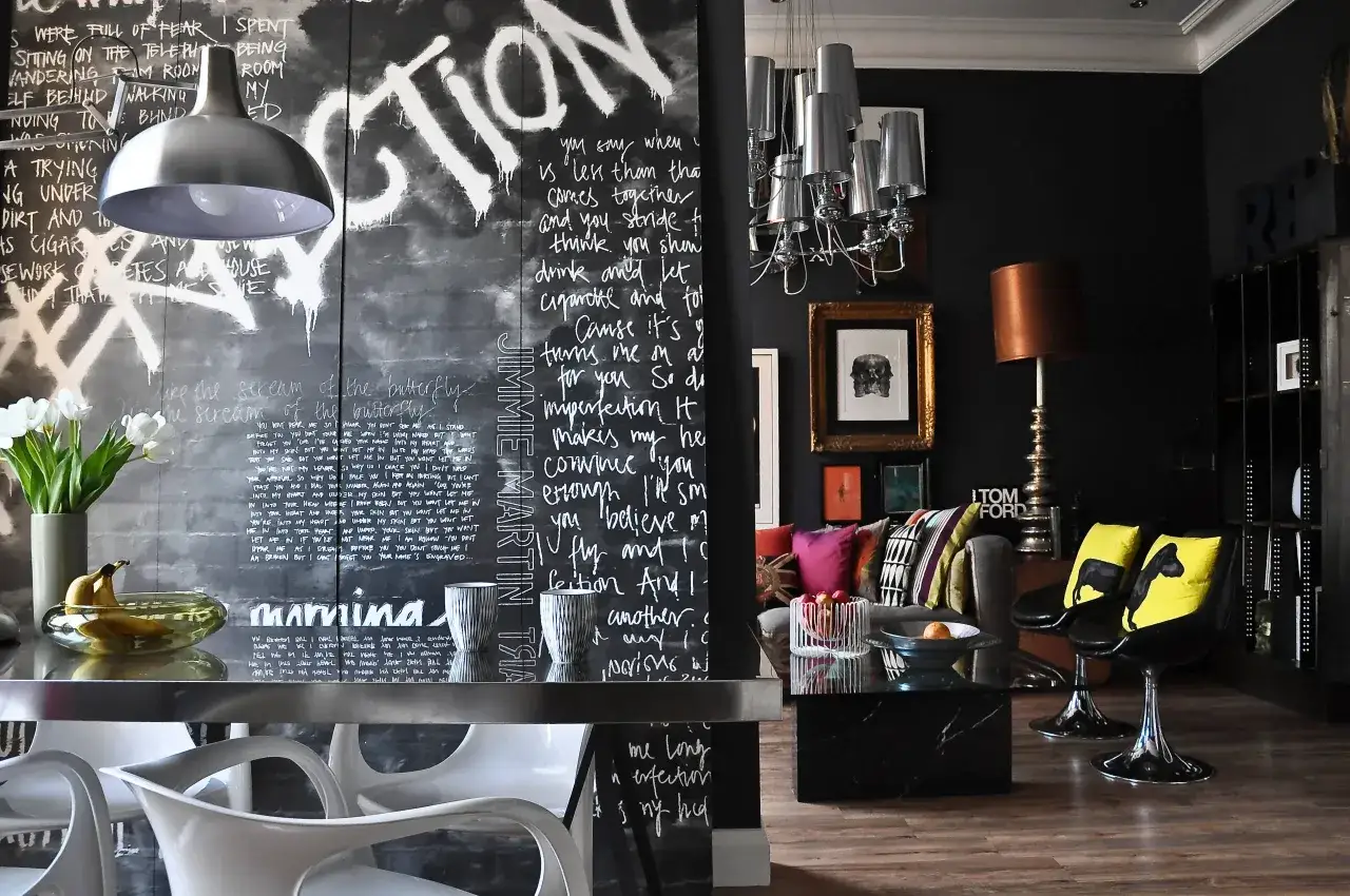 Parete lavagna con scritte artistiche e lampadario moderno. Idee per un soggiorno audace e creativo.