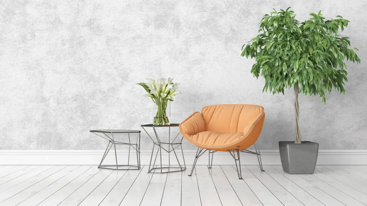 Sedia arancione, tavolini in metallo, fiori bianchi e pianta verde su sfondo con texture che ricorda i tipi di pittura per interni.