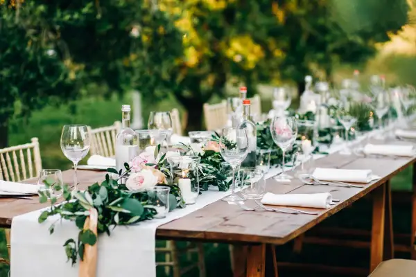 Tavola apparecchiata all'aperto con fiori, candele e bicchieri. Un'idea per le decorazioni matrimonio fai da te.
