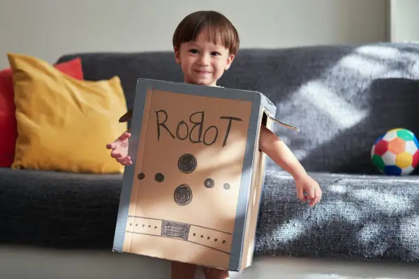 Bambino sorridente con travestimenti cartoni animati fai da te da robot, creato con una scatola di cartone.