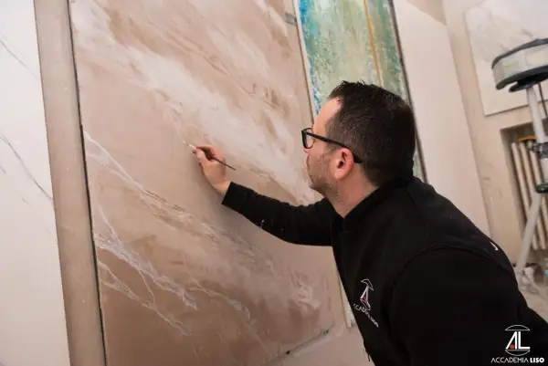 Artista crea effetti materici su pannello, mostrando diversi tipi di pittura per interni.
