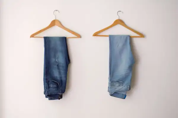 Due paia di jeans appesi: uno scuro, l'altro chiaro. Scopri come scolorire i jeans senza candeggina per ottenere questo effetto.