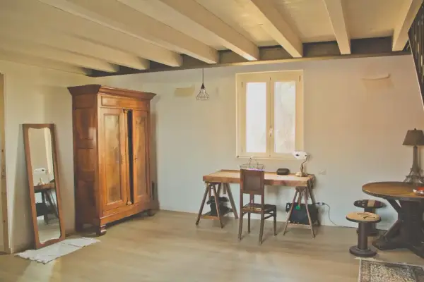 Arredare casa in campagna fai da te: armadio antico, specchio, scrivania rustica e tavolino con sgabelli.