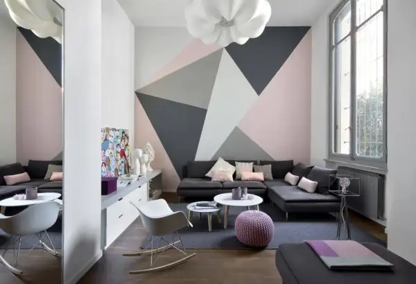Soggiorno moderno con parete decorata con motivi geometrici in pittura rosa, grigio e bianco. Idee decorazioni pareti pittura per un look audace.