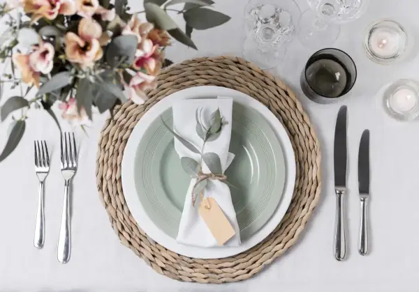 Tovagliolo decorato con rametto e cartellino, un'idea per portatovaglioli fai da te. Tavola apparecchiata con fiori, candele e posate.