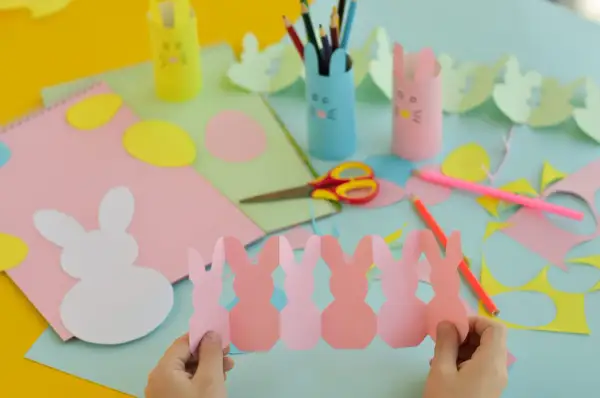Bambini creano lavoretti di Pasqua scuola primaria: coniglietti di carta, uova colorate e porta-matite a tema.