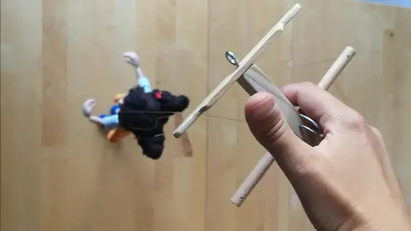 Mano che muove un marionette fai da te con fili di controllo in legno.