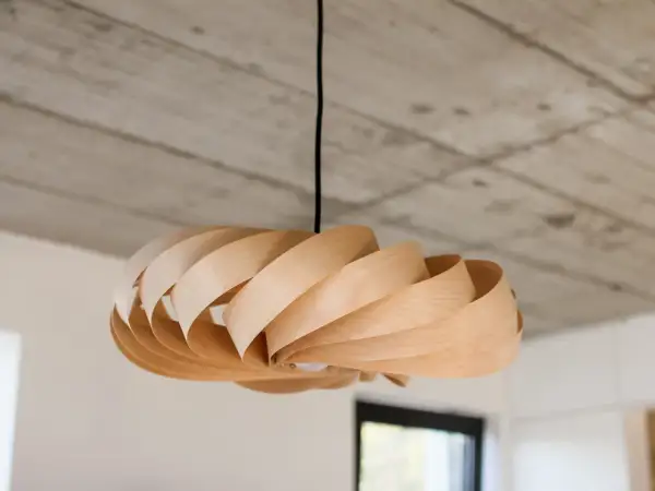 Lampadario in legno fai da te, con lamelle curve che creano un effetto a spirale. Luce soffusa e design naturale.