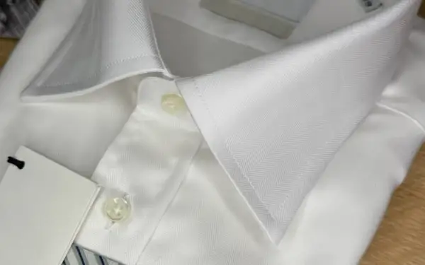 Dettaglio di una camicia bianca con colletto e bottoni. Un'idea su come sbiancare una camicia bianca ingiallita.